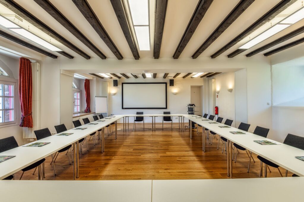 Artur-Winkelmann-Saal mit Leinwand und Tischen in U-Form